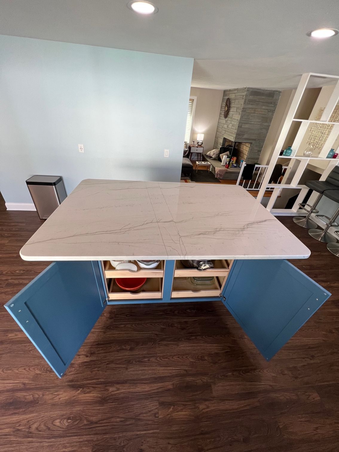 Open blue cabinet with white tabletop in a room with dark wood flooring