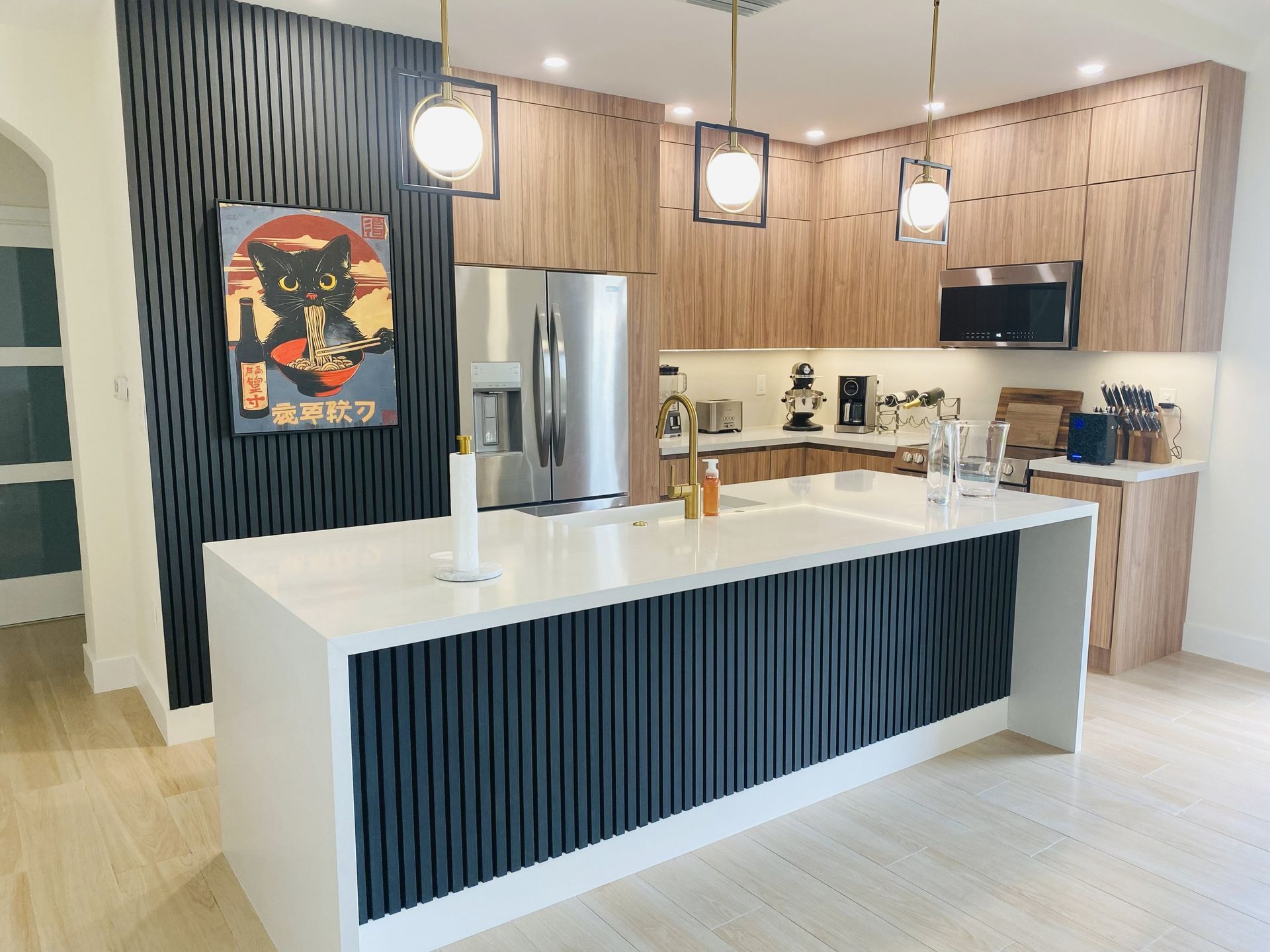 Modern kitchen with white island, black accent wall and wood cabinets; stainless steel appliances.
