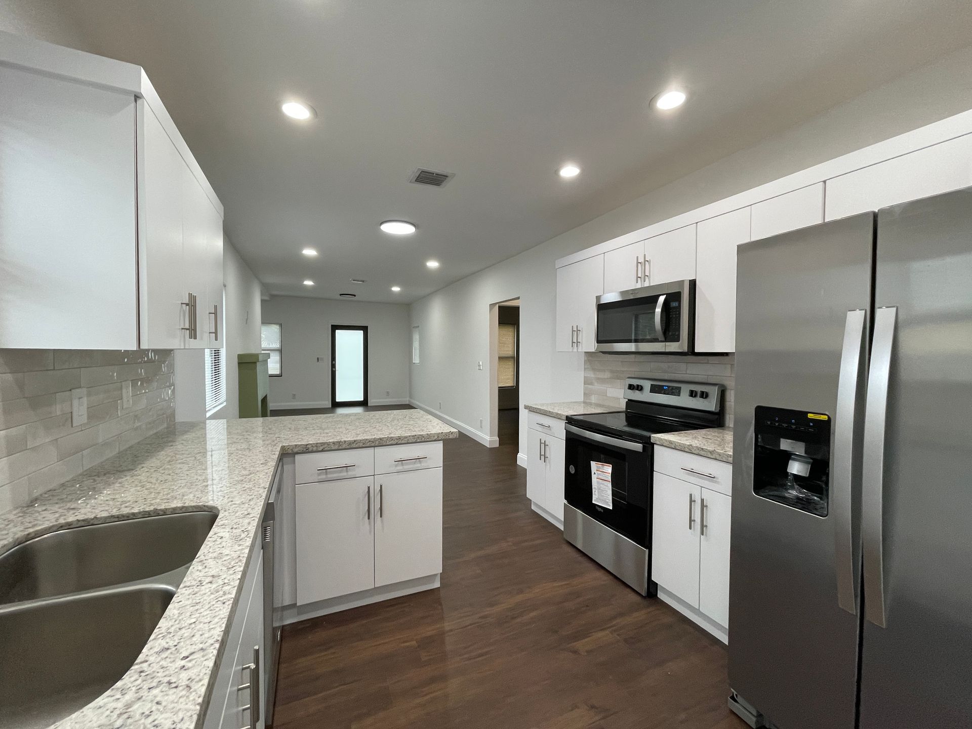 Modern kitchen with white cabinets, stainless steel appliances, and granite countertops.
