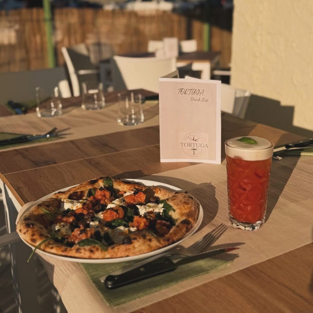 Pizza e bibita rossa su un tavolo in un ristorante all'aperto.