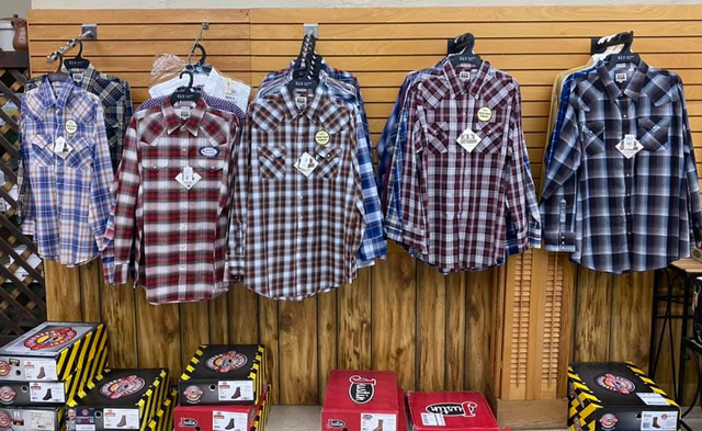 A row of plaid shirts are hanging on a wall in a store.