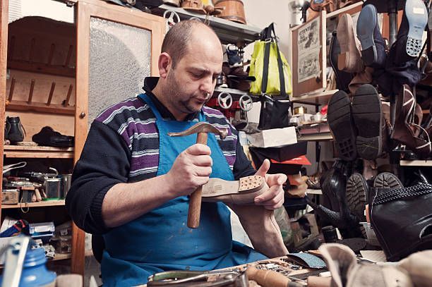 A man is working on a shoe in a shoemaker 's shop.