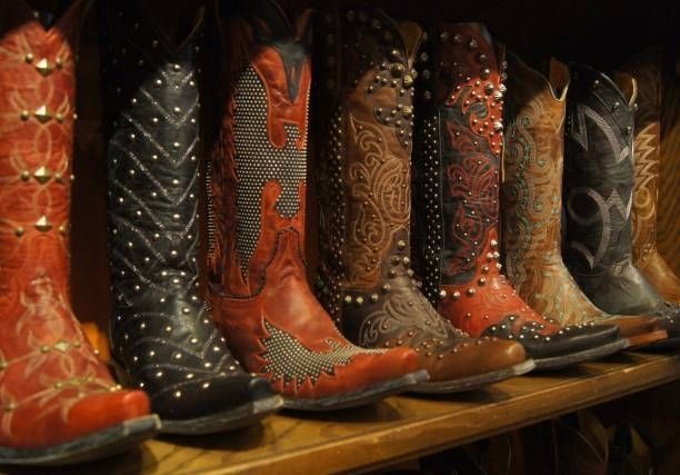 A row of cowboy boots are lined up on a wooden shelf.