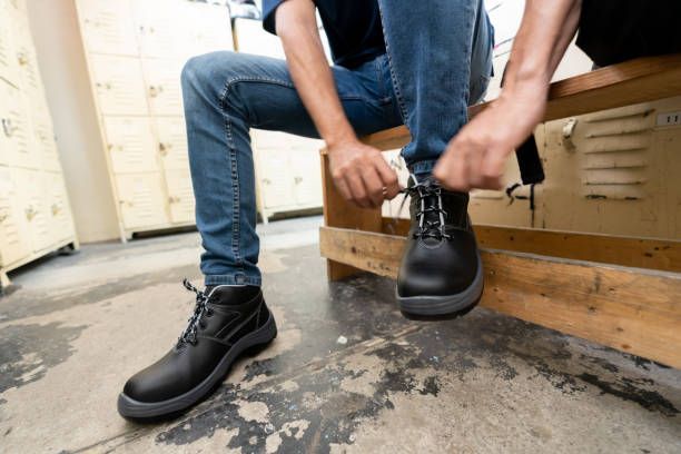 A man is sitting on a wooden bench tying his shoes.