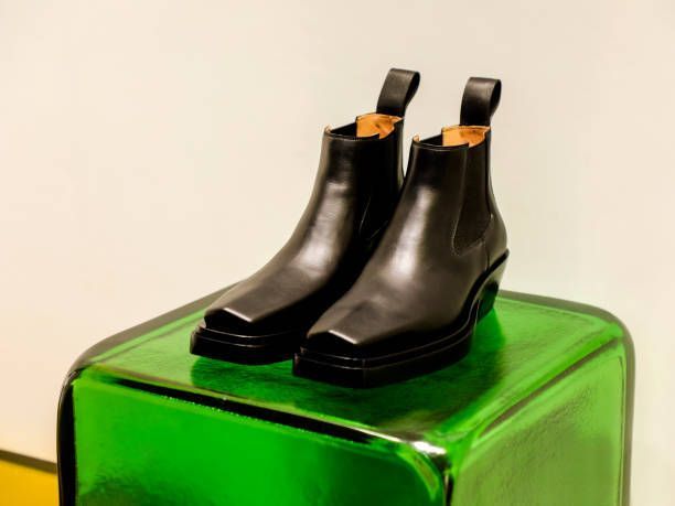 A pair of black boots are sitting on top of a green cube.