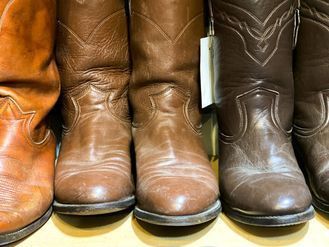 A row of brown cowboy boots are lined up on a table.