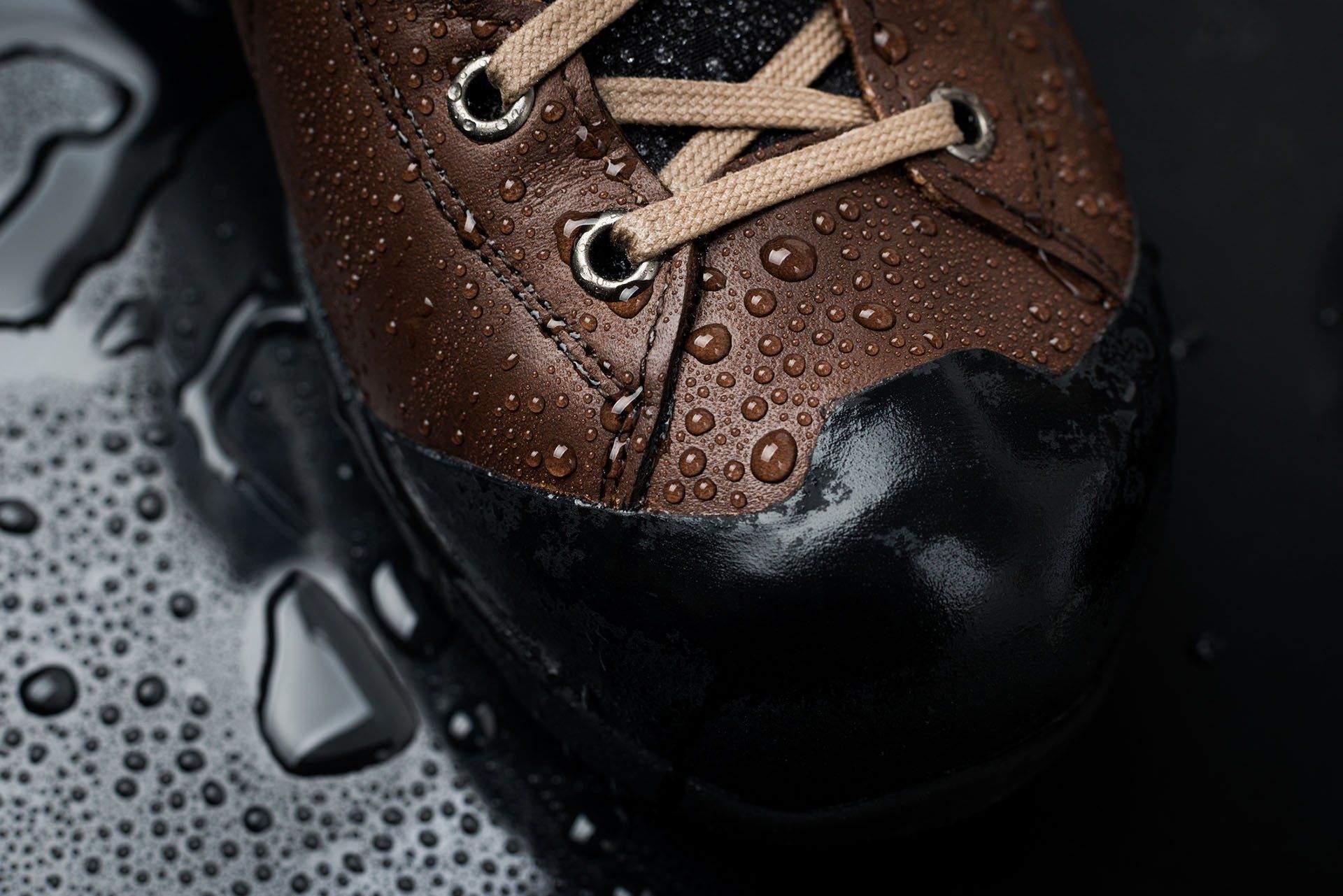 A close up of a brown shoe with water drops on it.
