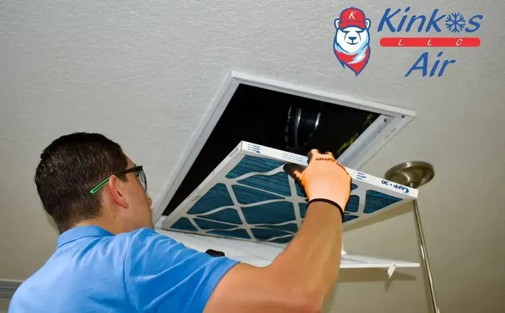Technician in blue shirt replacing an attic air vent cover with a screwdriver