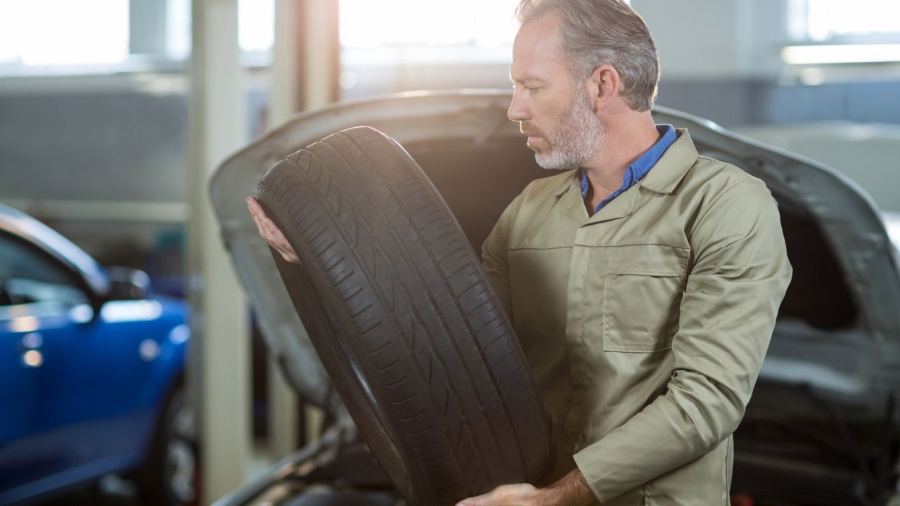Mechanic checking tire tread wear during a vehicle tire inspection service