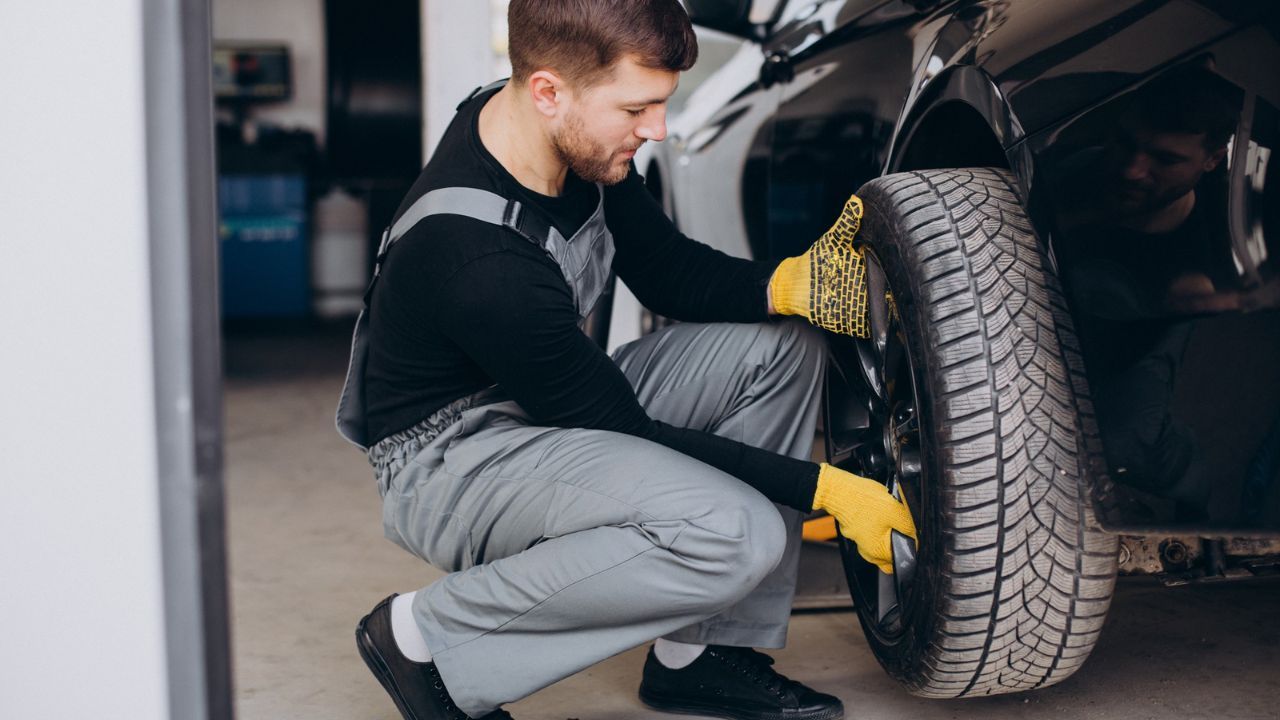 Tire repair technician inspecting and replacing a car tire in an auto garage