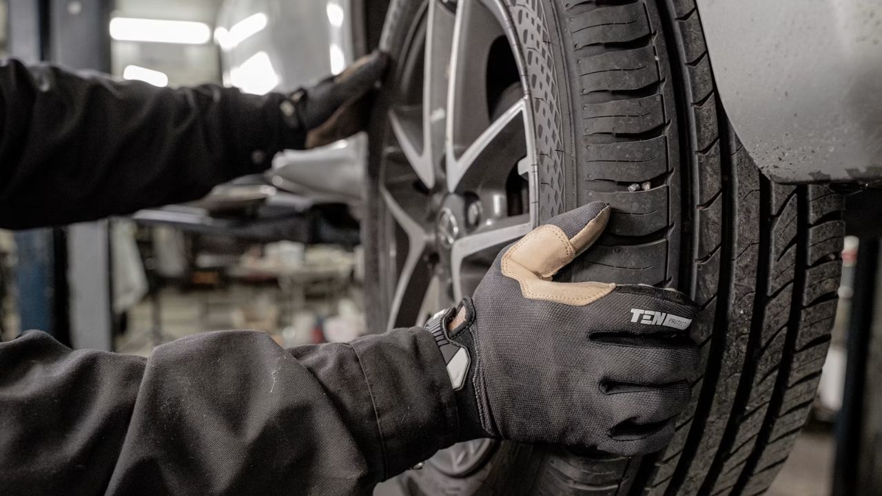 Automotive technician inspecting tire tread depth and wear patterns
