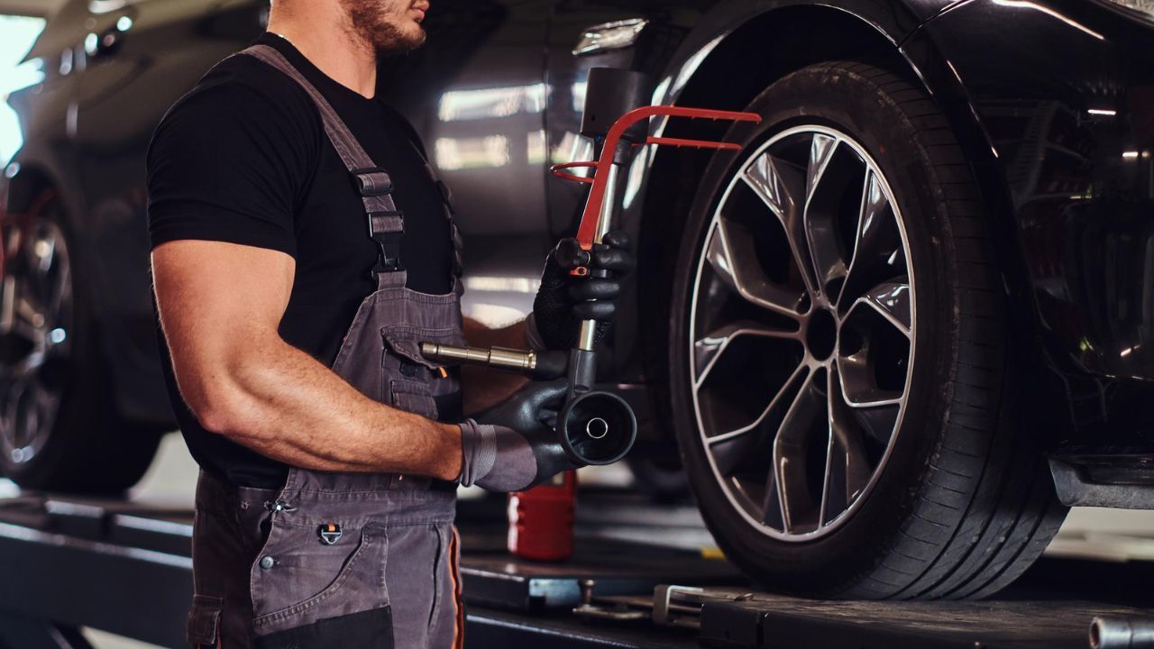 Professional mechanic performing wheel alignment and tire service
