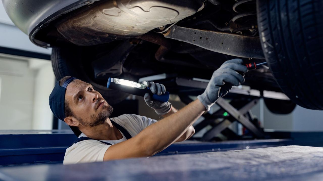 Technician checking underside of car during suspension inspection
