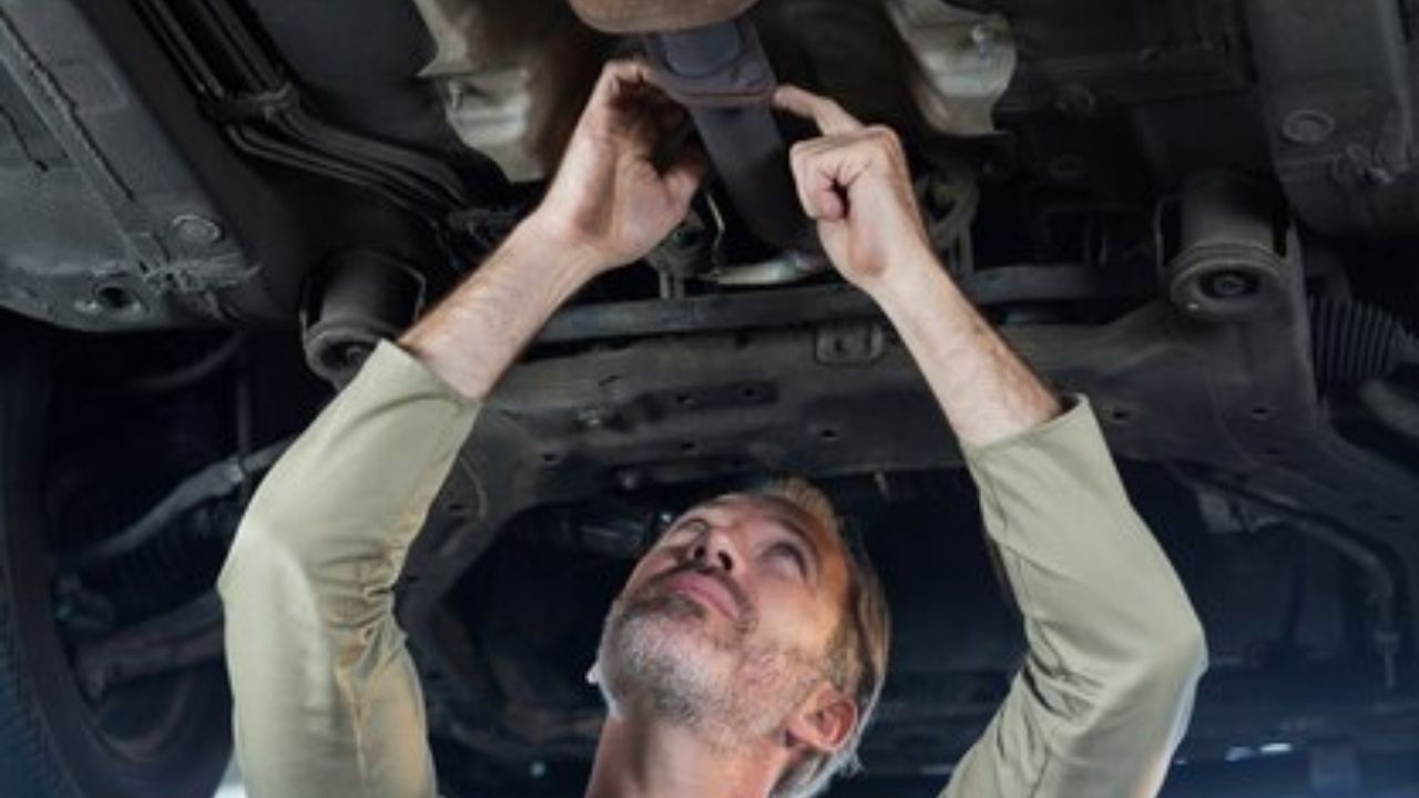 A man looking under the car for gas leakage
