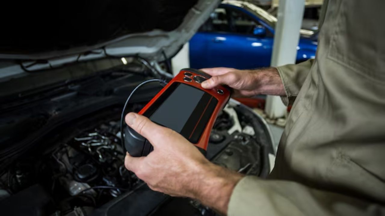 A mechanic checking the engine with his digital tool.