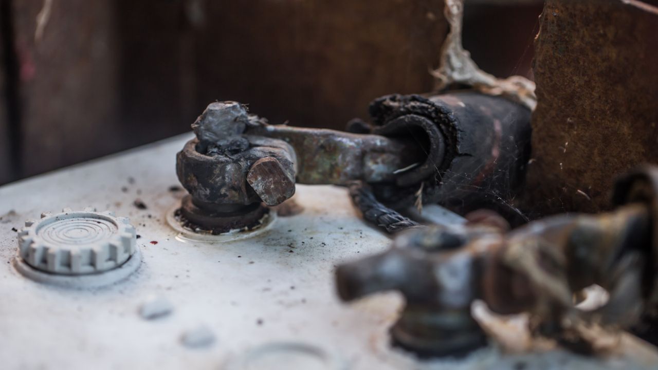 Close-up of corroded car battery terminals with visible damage