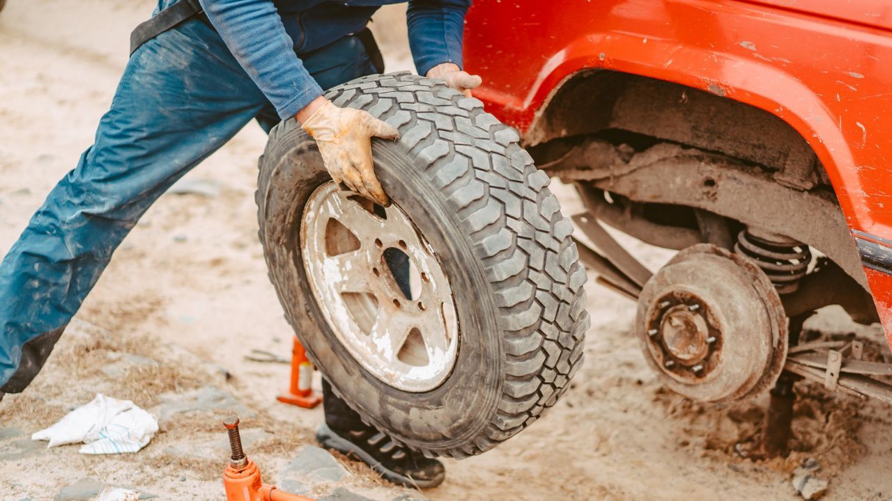 Manual tire replacement process on lifted vehicle with tools

