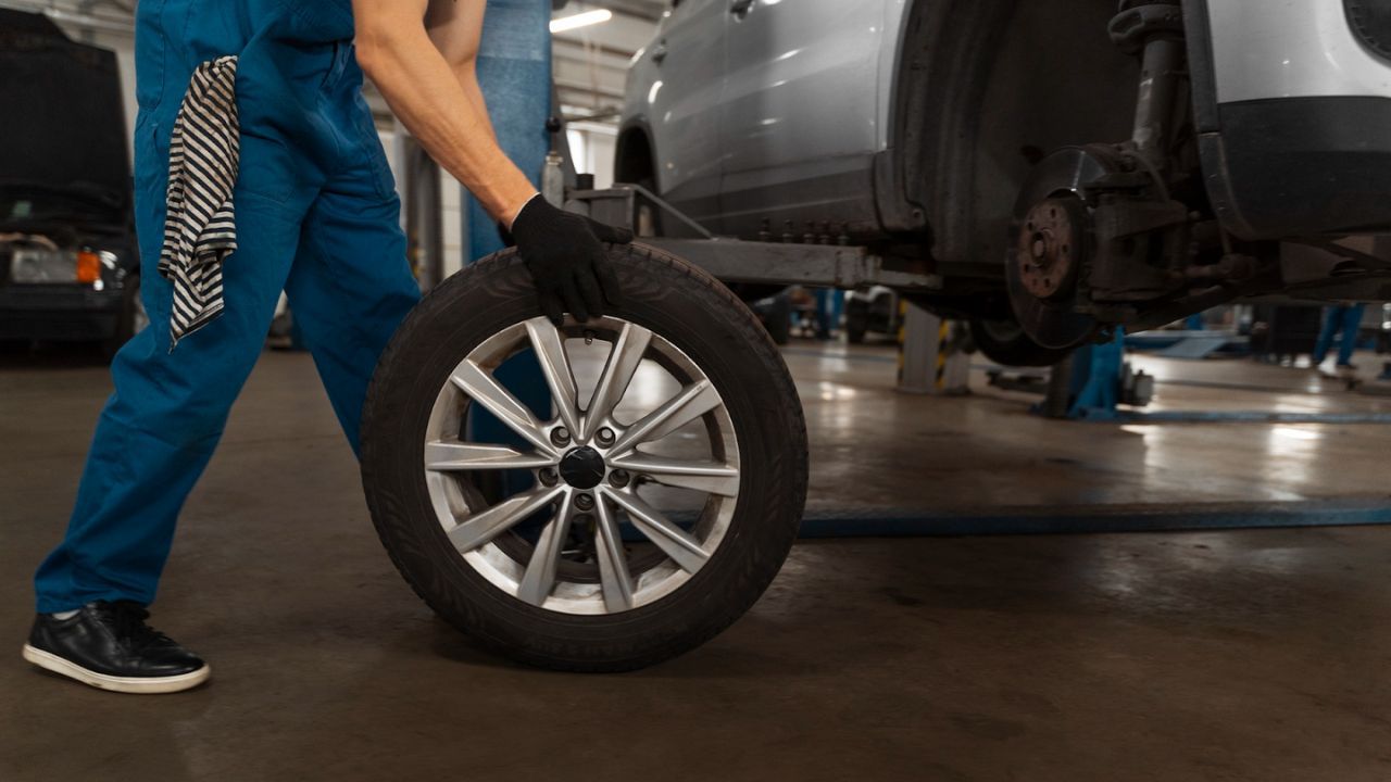Technician carrying tire in auto repair shop