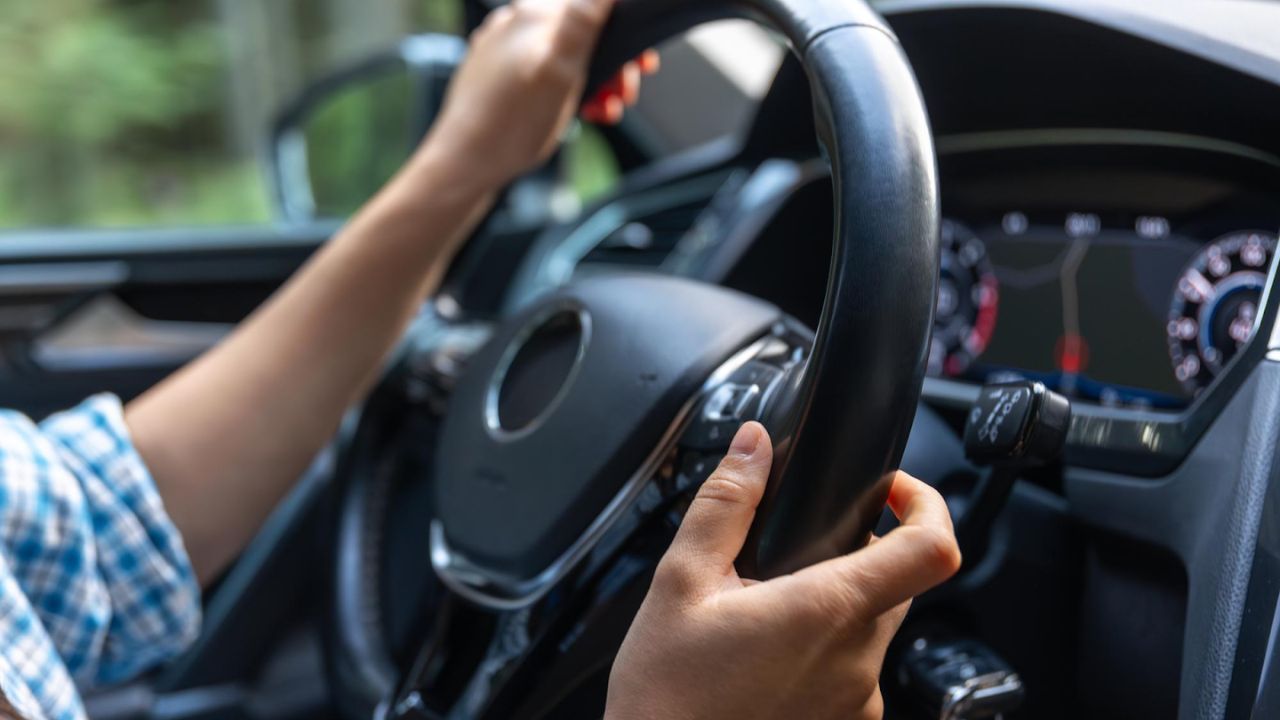 Driver holding steering wheel inside a car