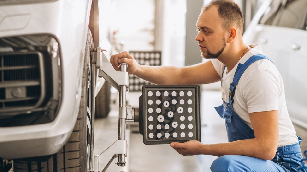 Technician performing wheel alignment on vehicle