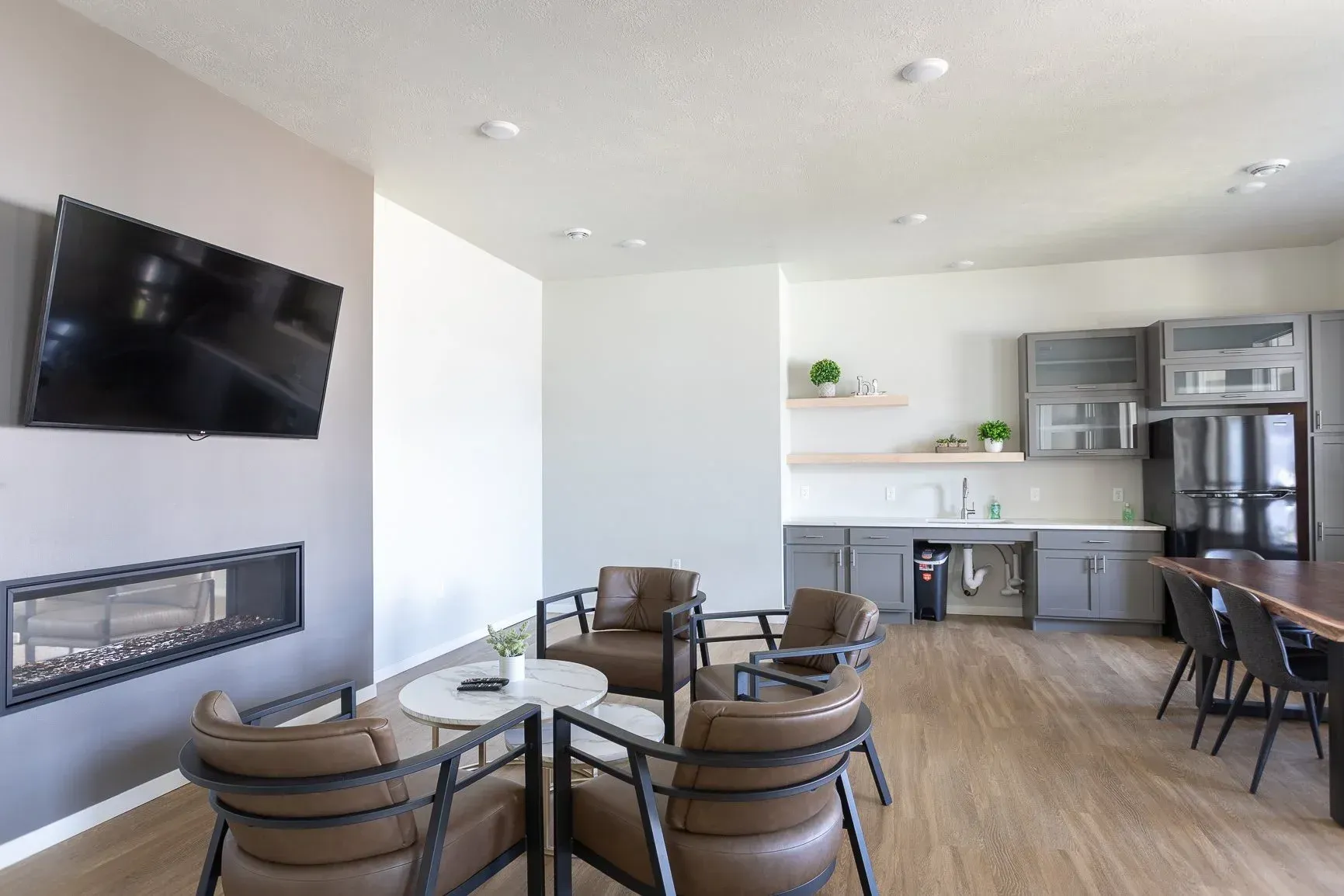 A living room with a fireplace , chairs , tables and a flat screen tv.