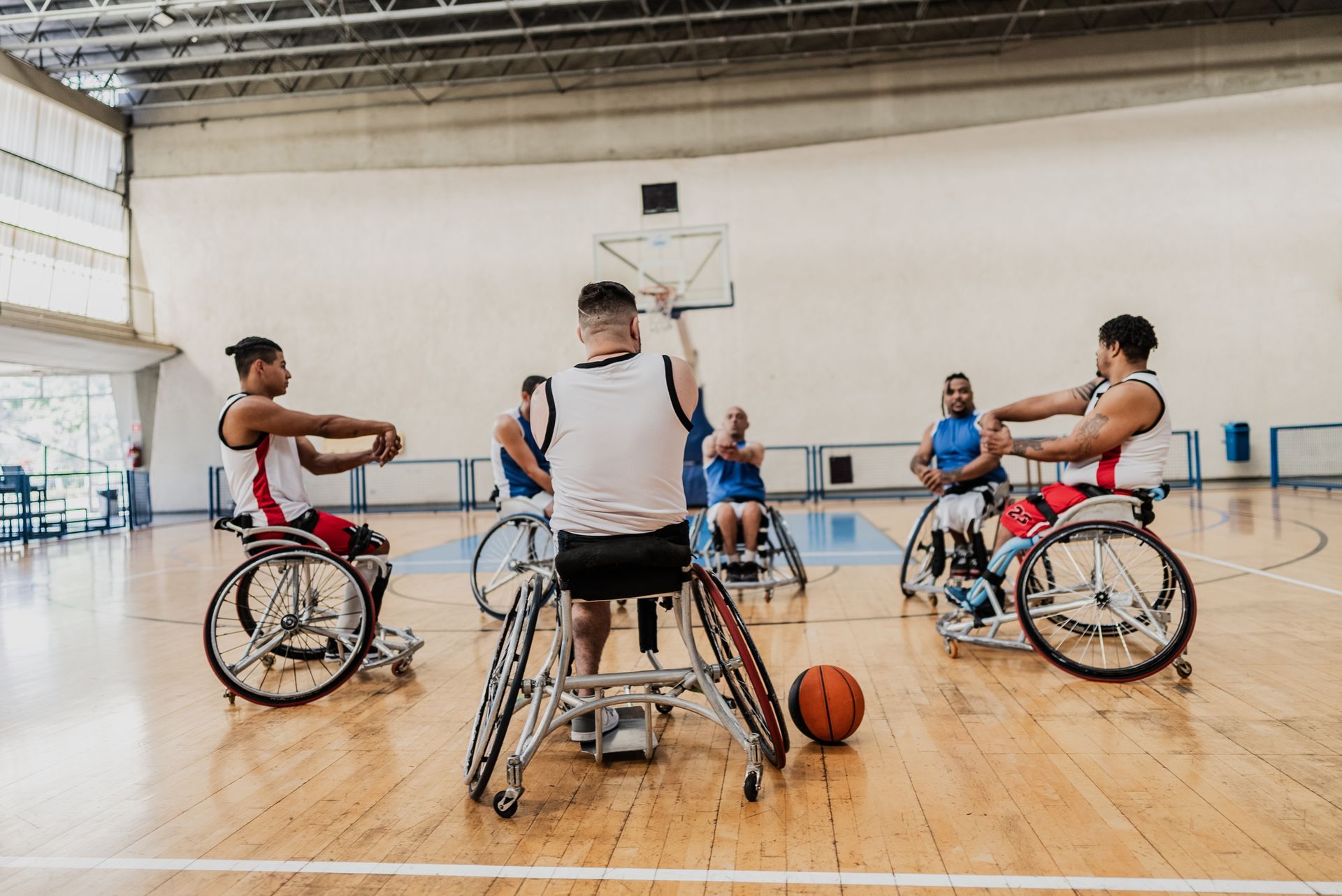 A group of people in wheelchairs are playing basketball on a court.