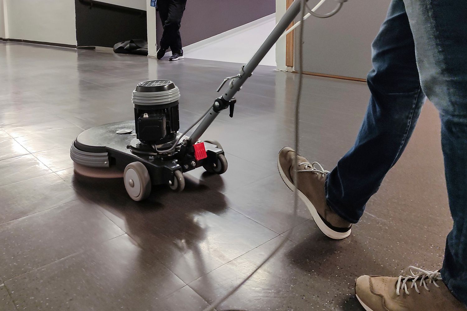Person operating a floor buffer machine on a polished floor. Person operating a floor buffer machine on a polished floor.
