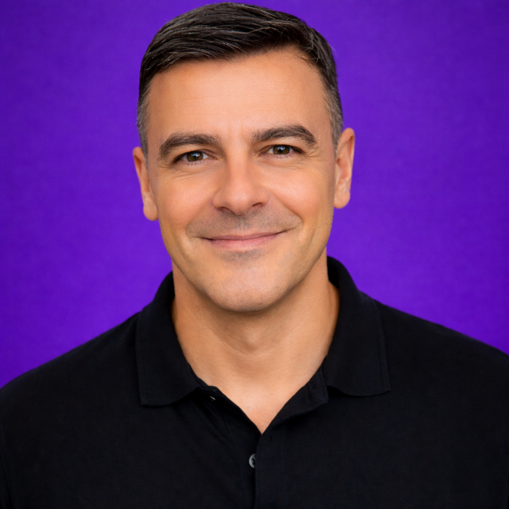 Man in black shirt smiles against a purple background.