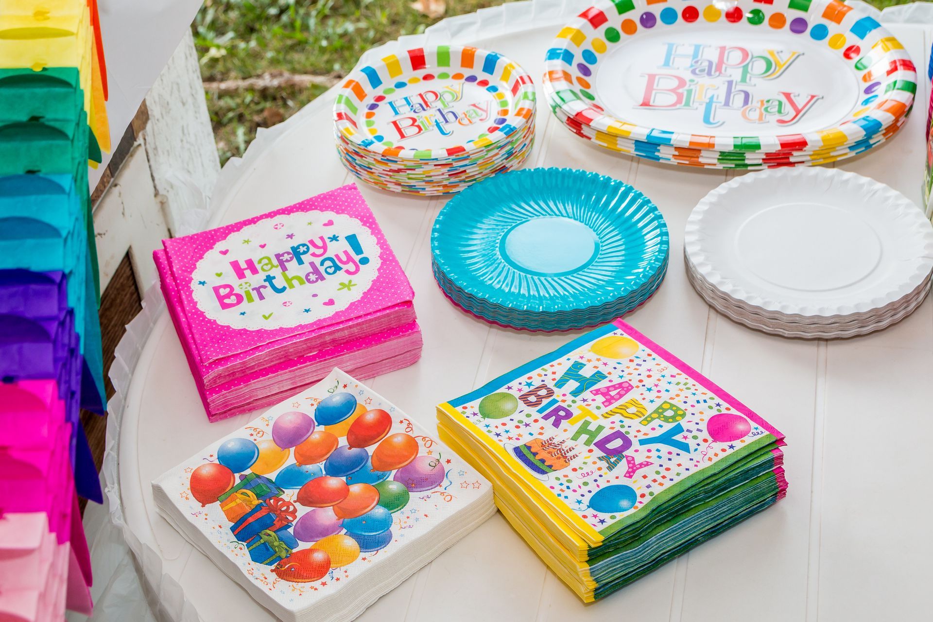Un tavolo apparecchiato con piatti di carta, tovaglioli e palloncini per una festa di compleanno.