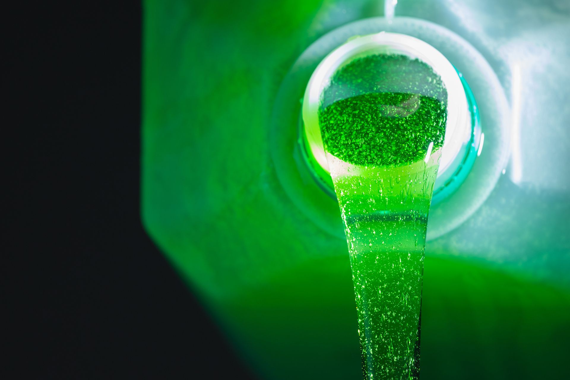 Un liquido verde fuoriesce da una bottiglia di plastica.