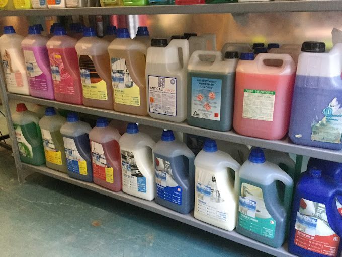 Diverse bottiglie di prodotti per la pulizia sono allineate su uno scaffale