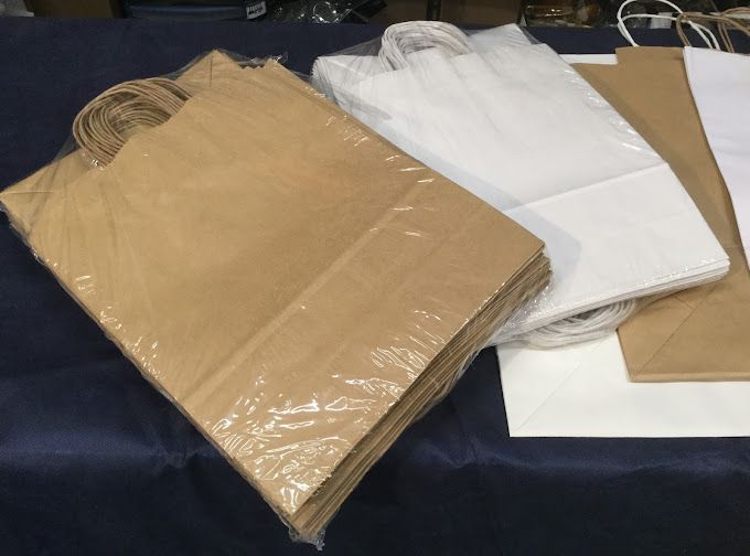 Una pila di sacchetti di carta marroni e bianchi su un tavolo