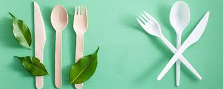 Utensili di legno e utensili di plastica con foglie verdi su sfondo verde.