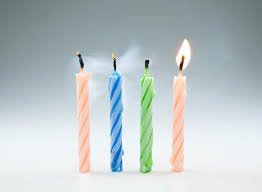 Quattro candeline di compleanno sono accese in fila su una superficie bianca.