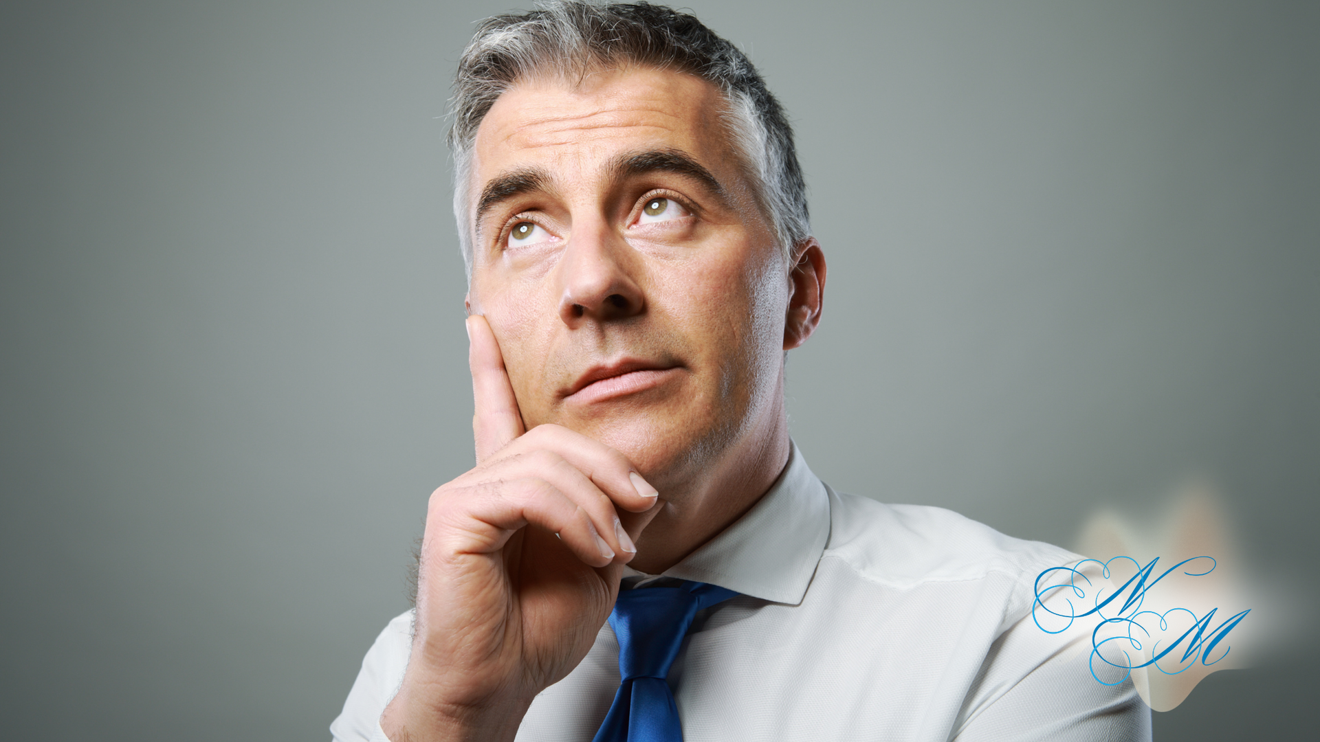 A man in a white shirt and blue tie is thinking with his hand on his chin.