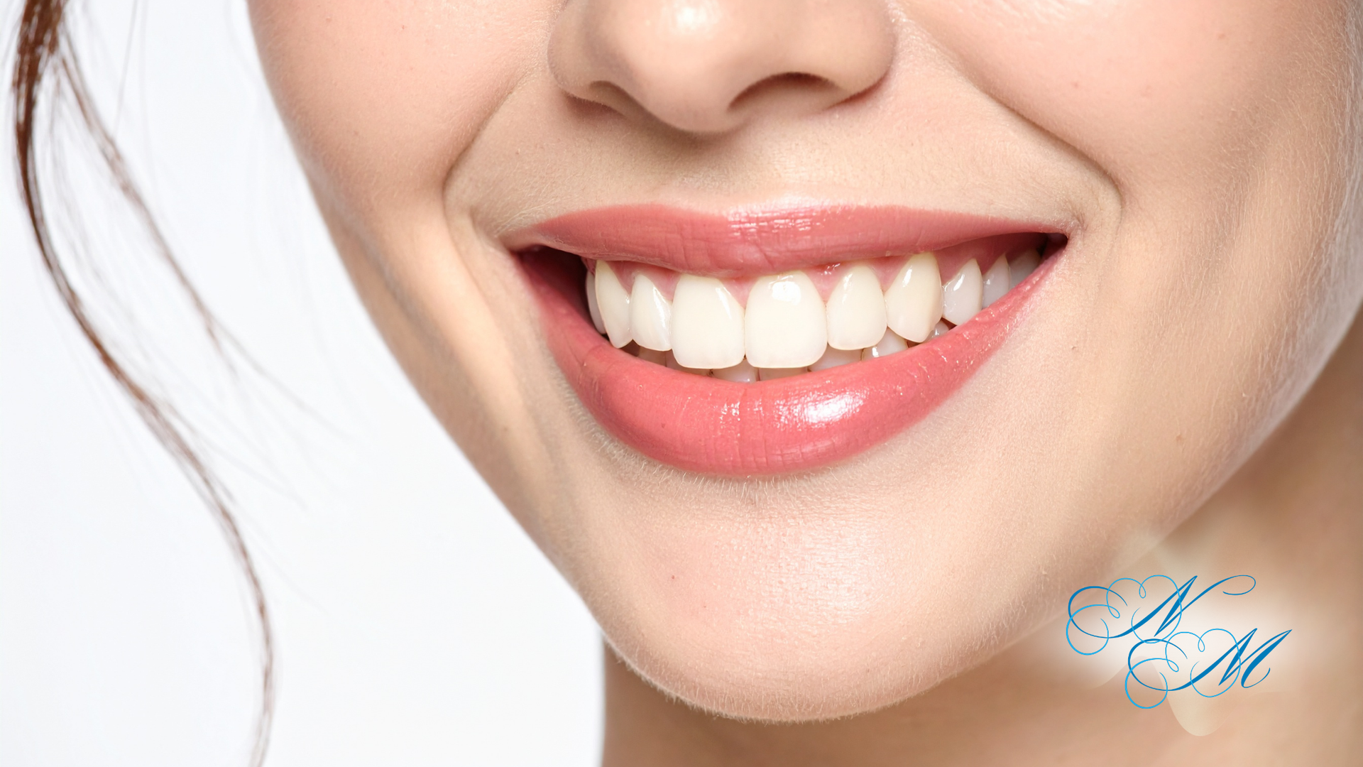 Close-up of a person's mouth, showing slightly discolored teeth and a mole on the chin.