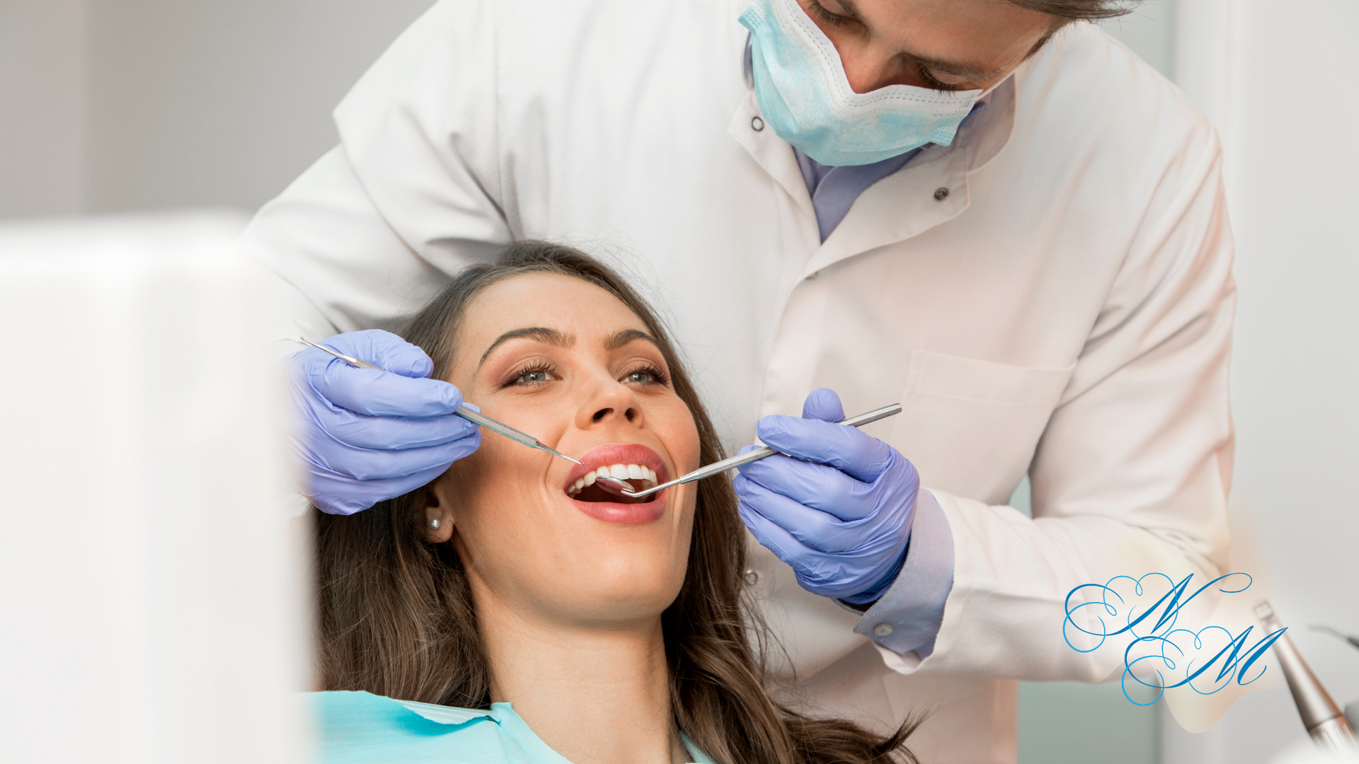 Dentist examining a woman's teeth. Both in medical attire, in a dentist's office.