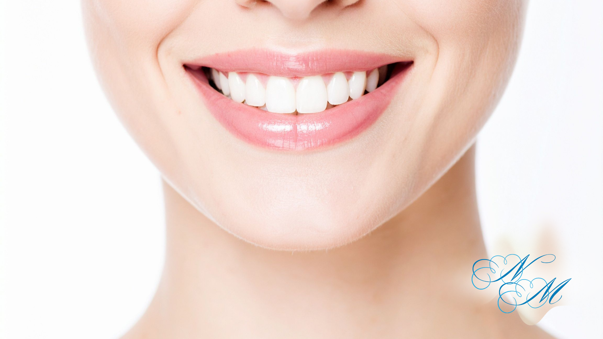 Close-up of a smiling mouth with bright white teeth and pink, glossy lips.