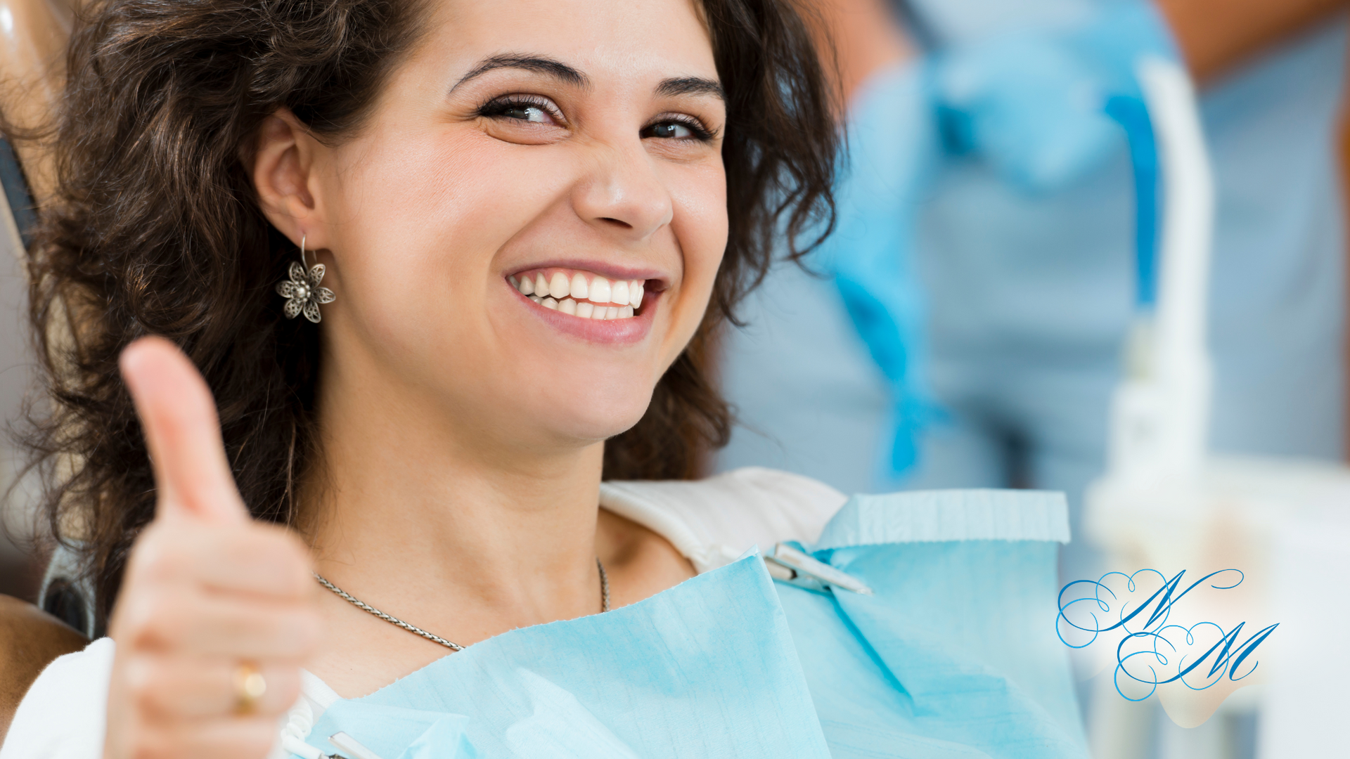 A woman is giving a thumbs up in a dental chair.
