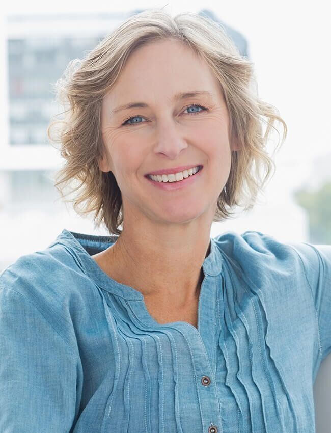 A woman in a blue shirt is smiling for the camera.