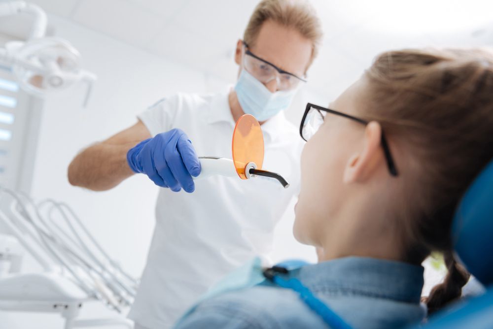 A dentist is examining a patient 's teeth in a dental office.