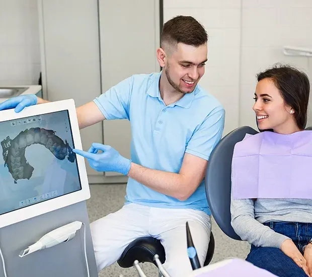 A dentist is showing a picture of a patient 's teeth on a computer screen.