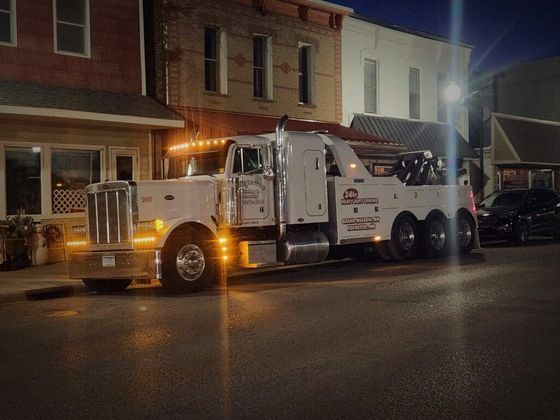 A tow truck is parked in front of a building at night