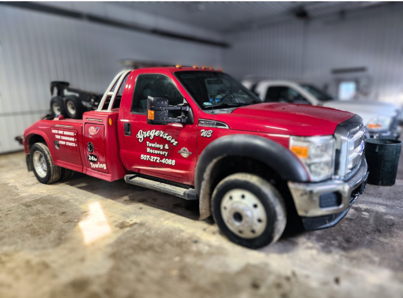 A red tow truck is parked in a garage