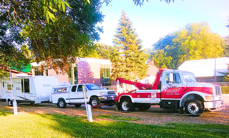Two tow trucks are parked next to each other in a grassy area.