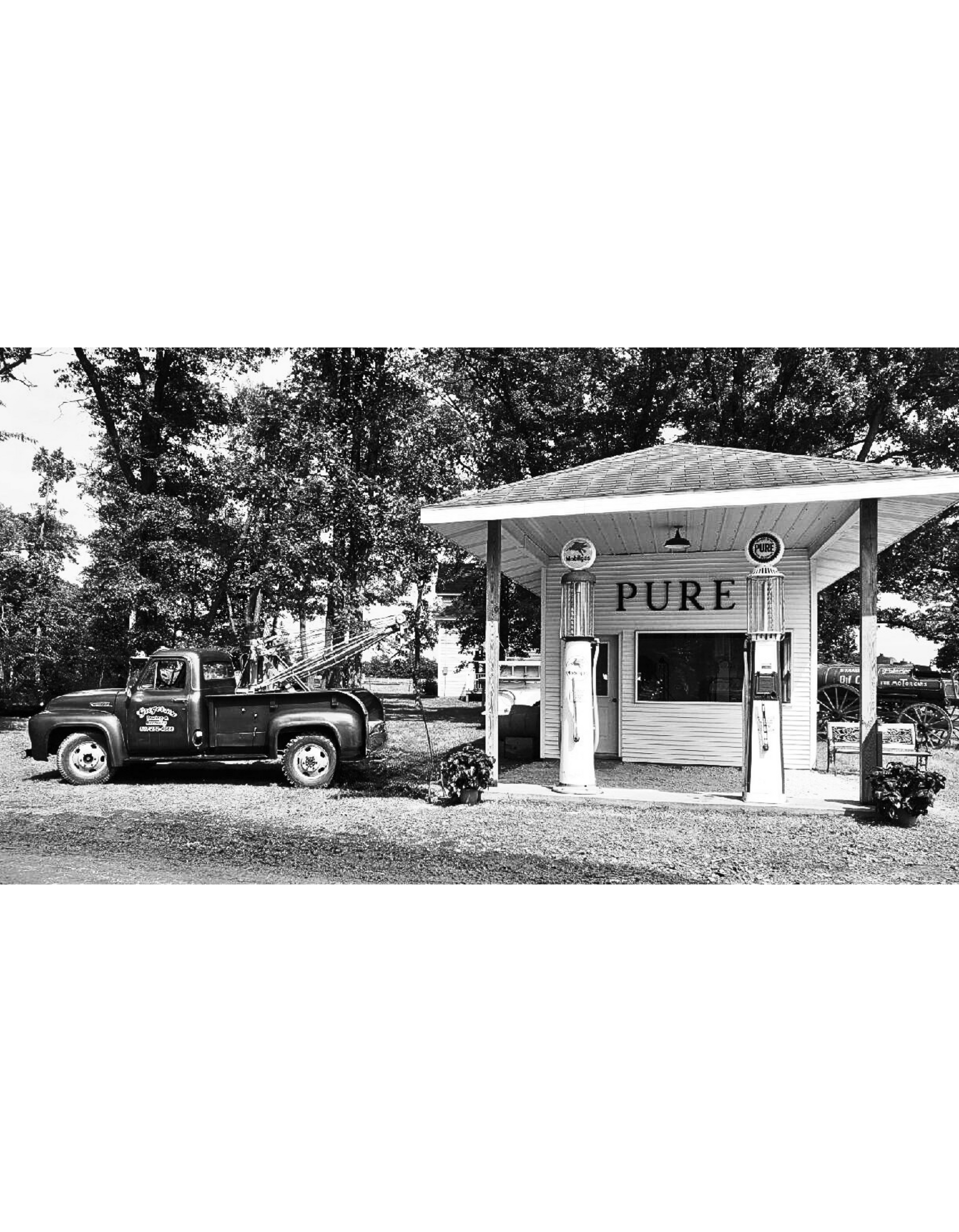 A black and white photo of a truck parked in front of a gas station.