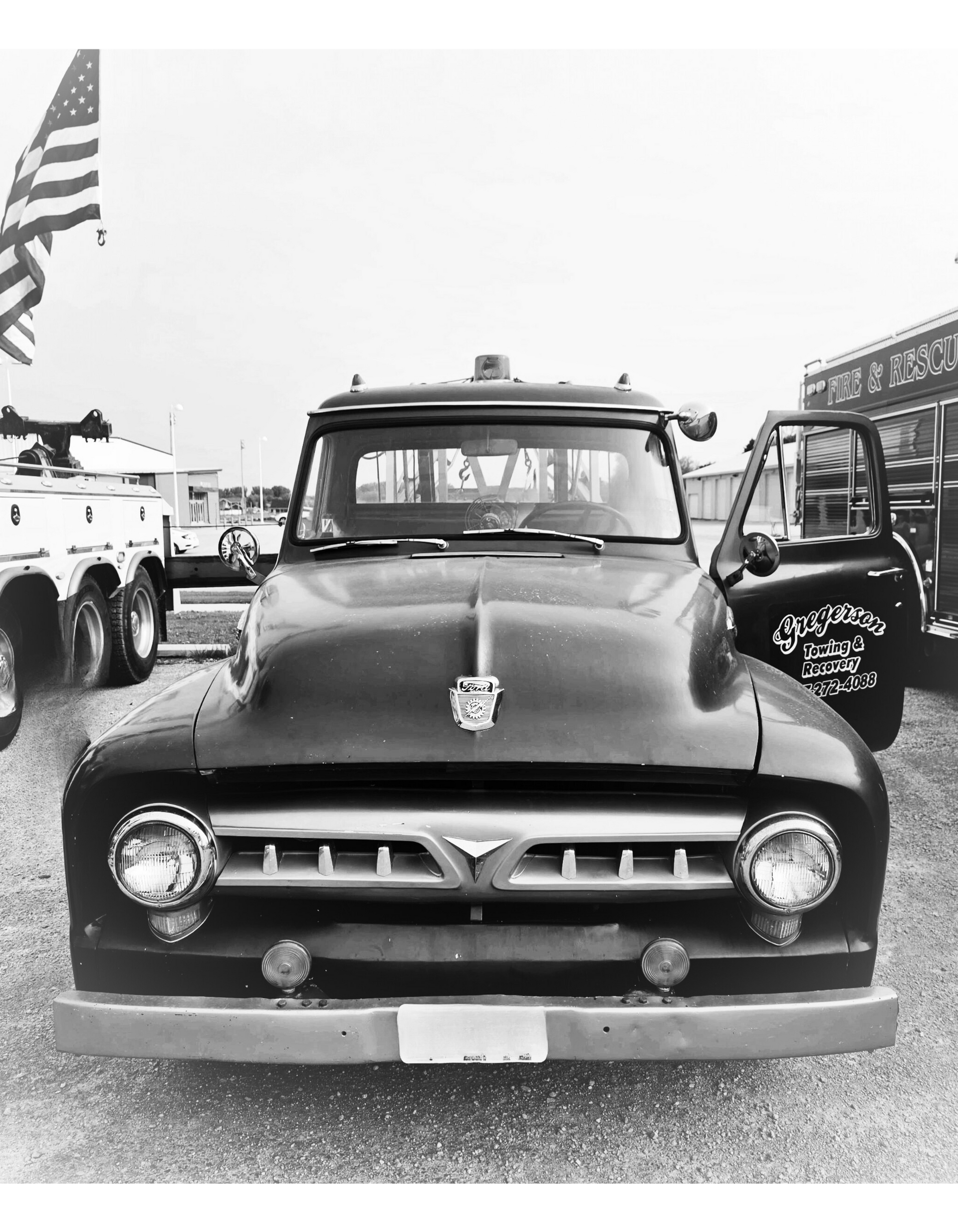 A black and white photo of an old ford truck parked in a parking lot.