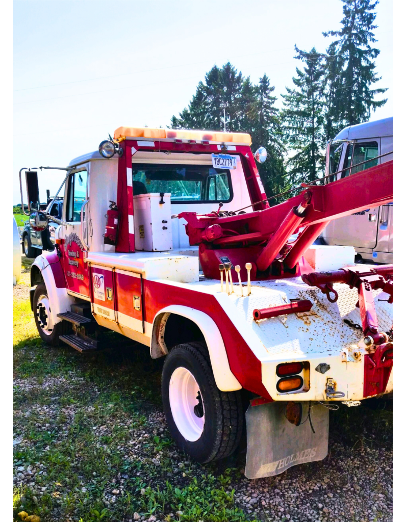 A red and white tow truck is parked in the grass