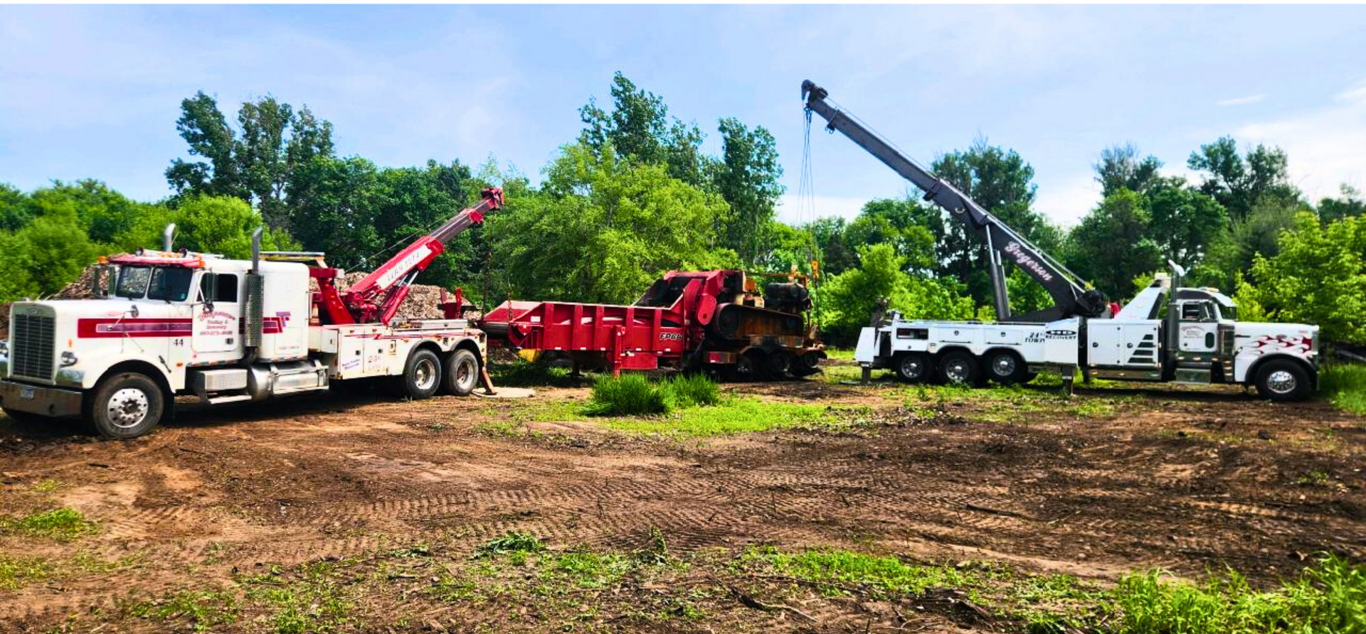 Two tow trucks are parked next to each other in a field.