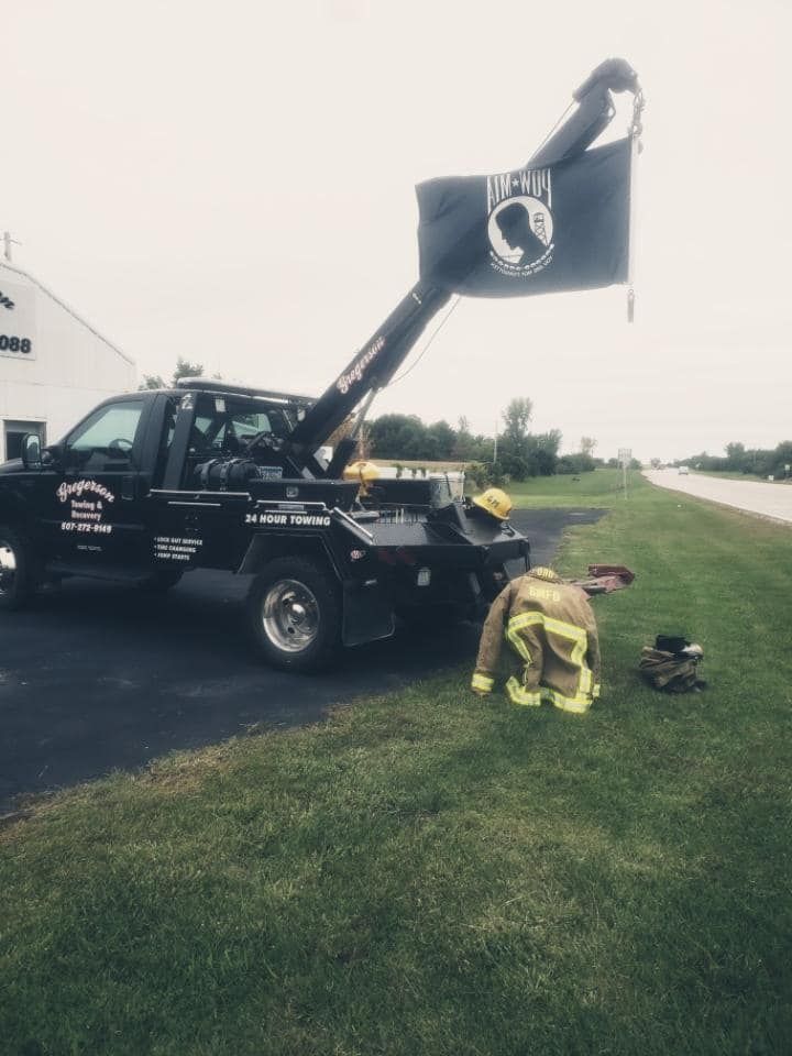 A firefighter is kneeling in front of a tow truck